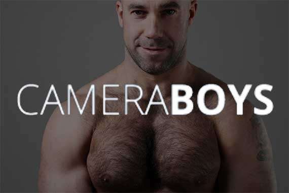 hombre calvo y musculoso con vello en el pecho, detrás del logo de Cameraboys